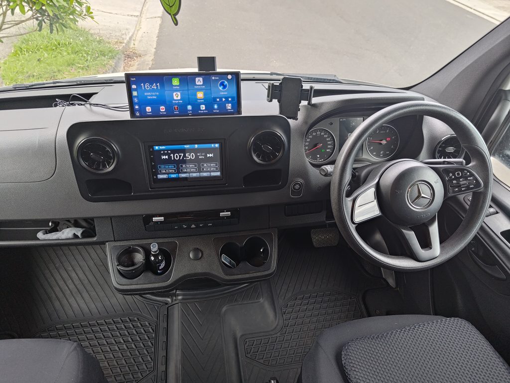 Upgraded Mercedes Sprinter dashboard with infotainment system and additional screen mounted for navigation and monitoring.