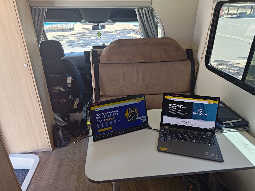 Mobile Dojo interior workspace with laptop and external monitor set up on the dinette table for remote work.